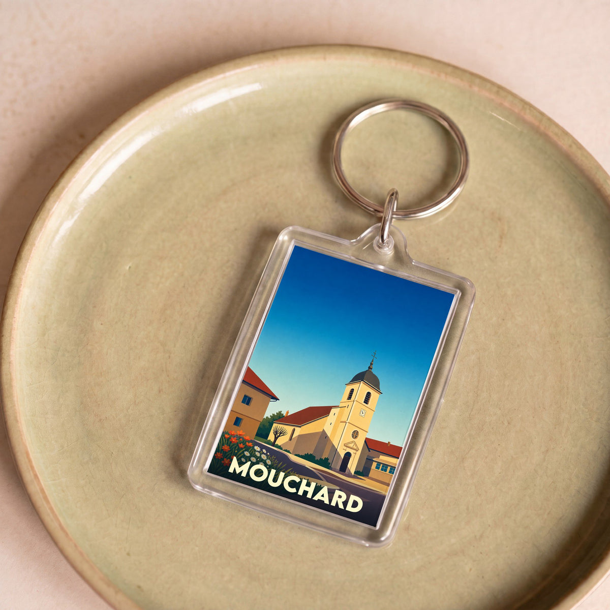 Porte-clés souvenir de la ville de Mouchard avec une illustration stylisée de son église.