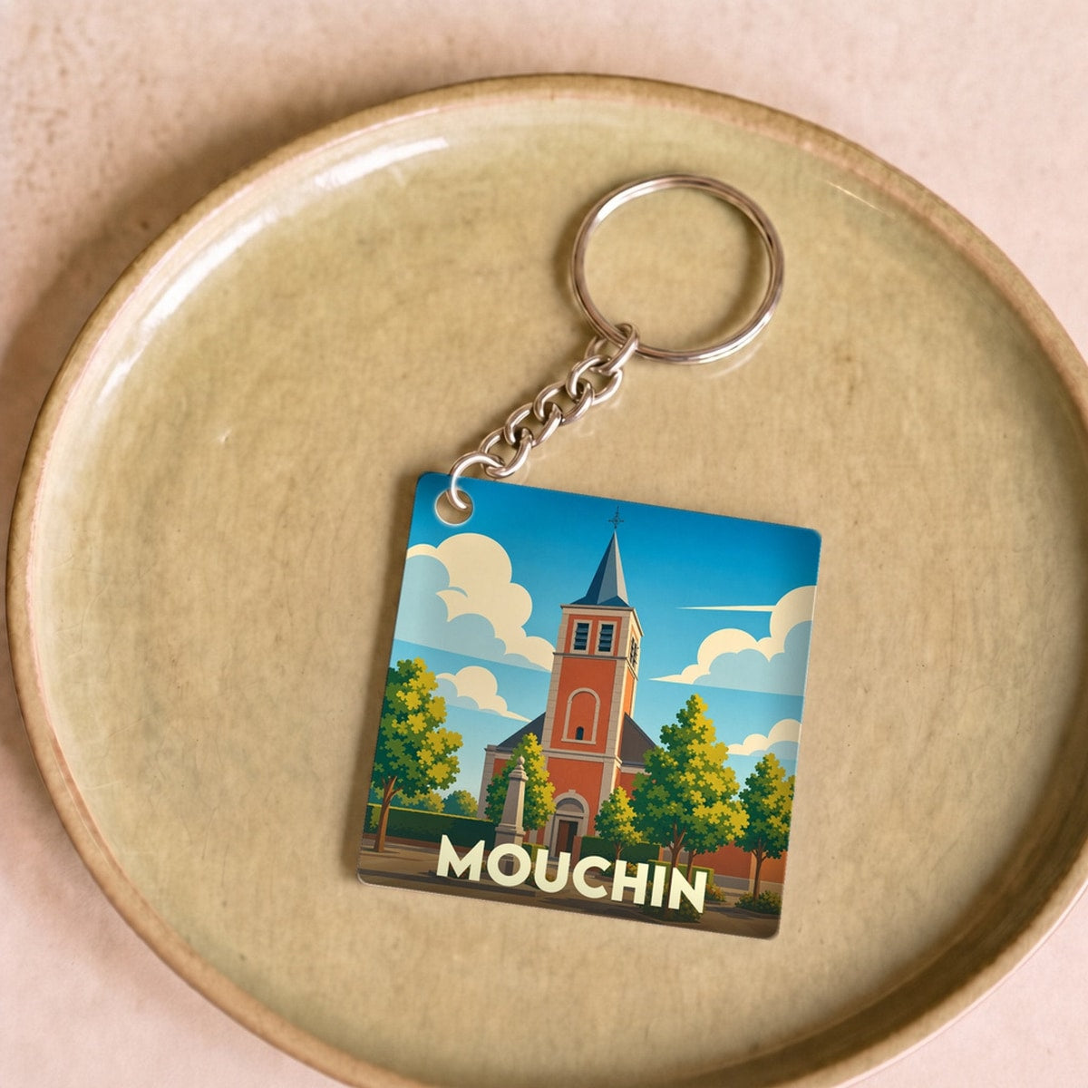 Porte-clés souvenir de la ville de Mouchin avec une illustration stylisée de son église.