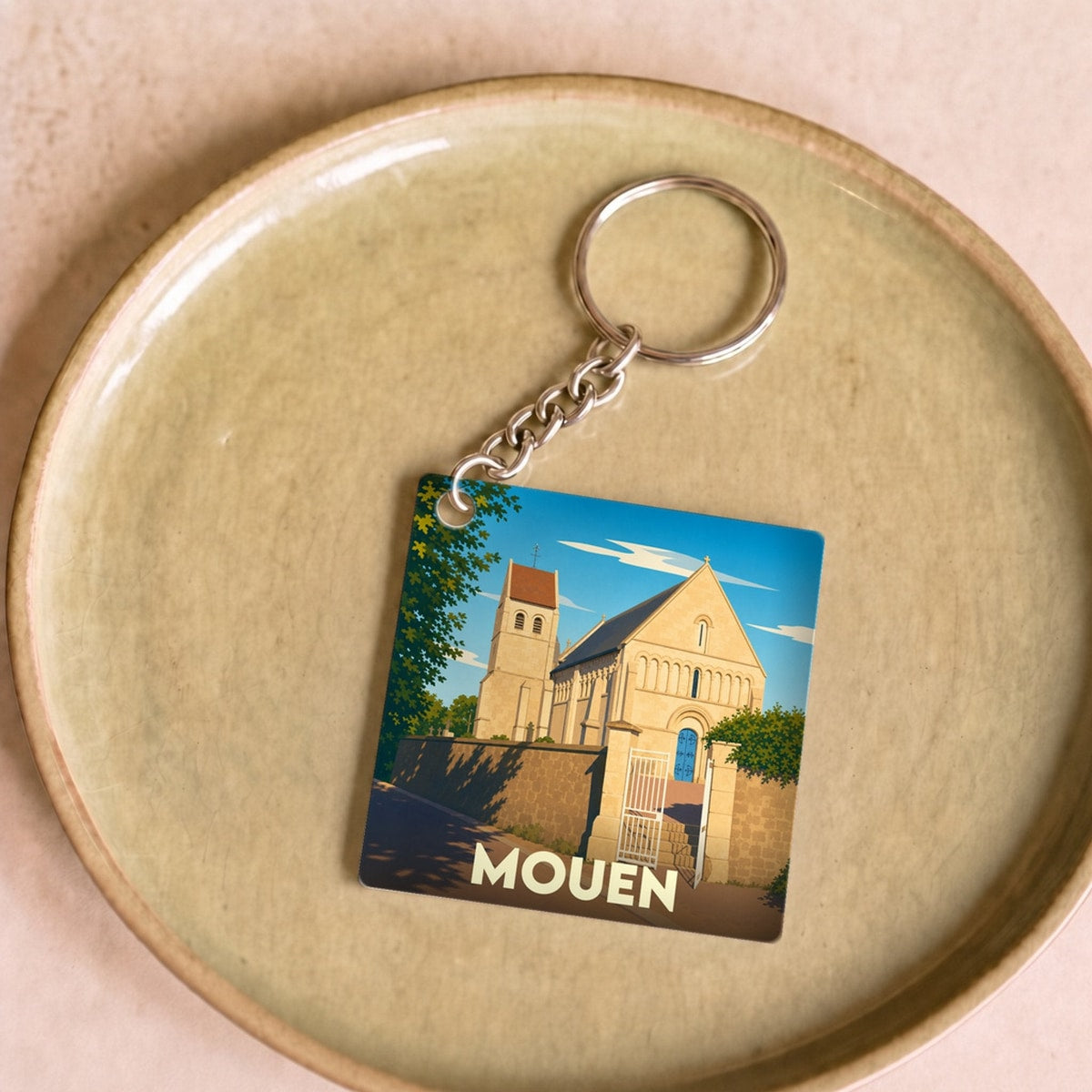 Porte-clés souvenir de la ville de Mouen avec une illustration stylisée de son église.