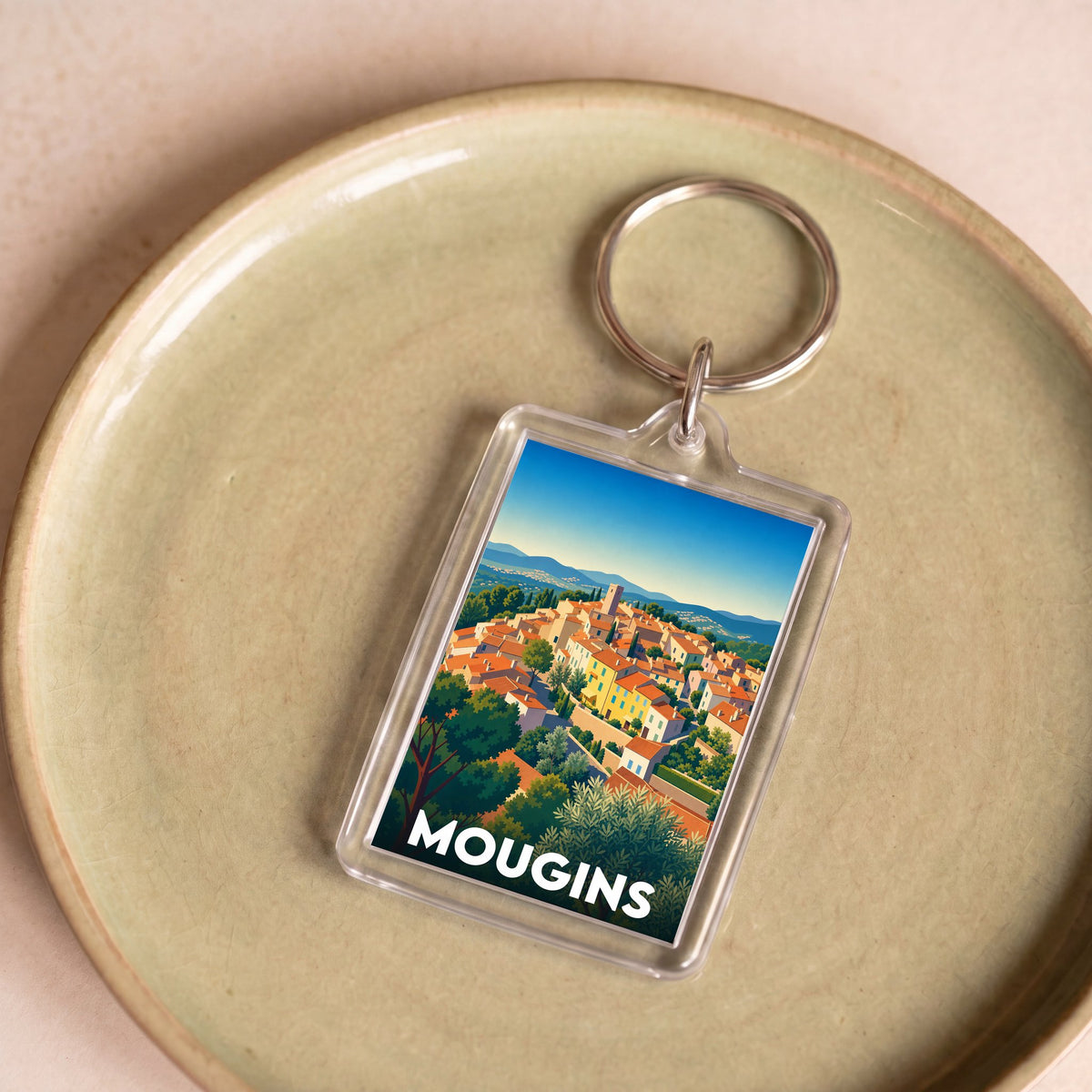 Porte-clés souvenir de la ville de Mougins avec une illustration stylisée du village.