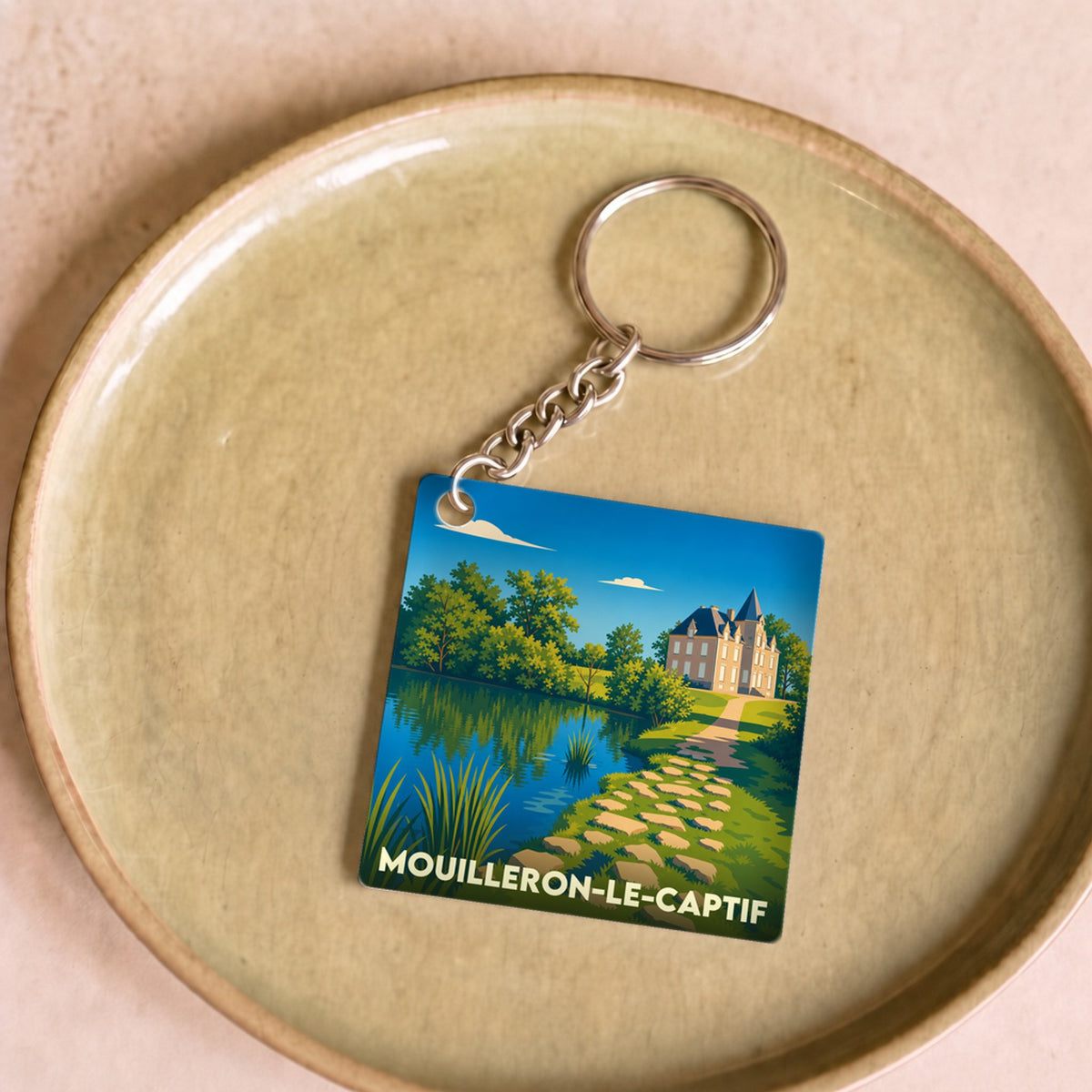 Porte-clés souvenir de la ville de Mouilleron-le-Captif avec une illustration stylisée d'un château au bord de l'eau.