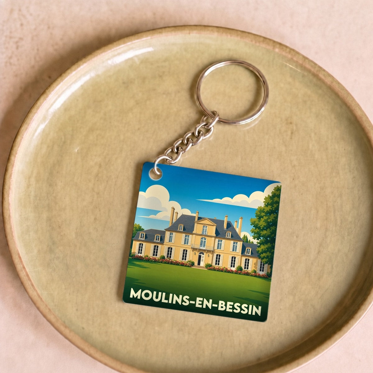 Porte-clés souvenir de la ville de Moulins-en-Bessin avec une illustration stylisée d'un château.