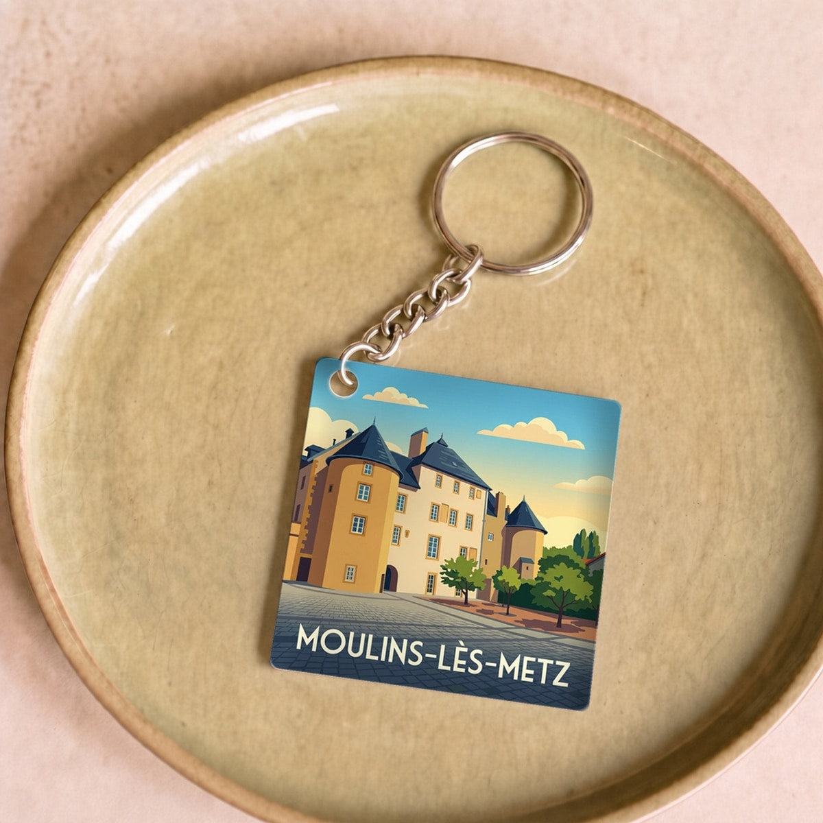Porte-clés souvenir de la ville de Moulins-lès-Metz avec une illustration stylisée.
