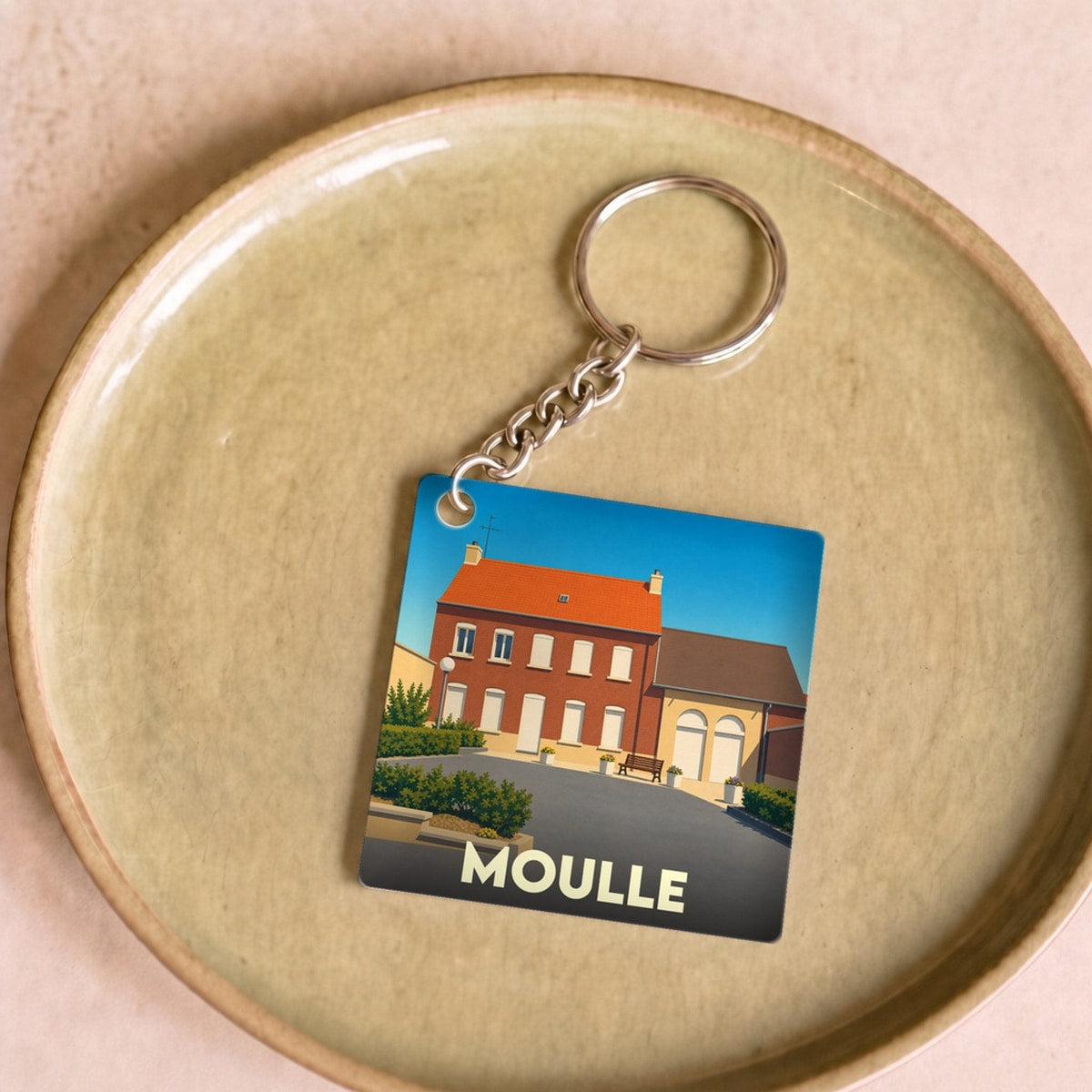 Porte-clés souvenir de la ville de Moulle avec une illustration stylisée d'un bâtiment local.