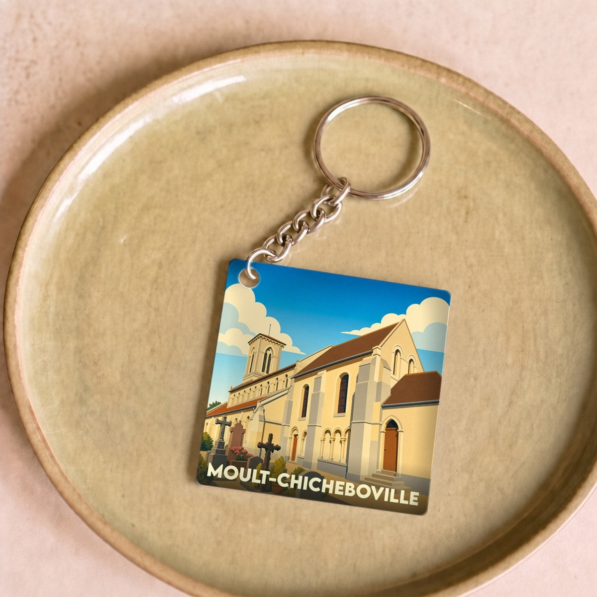 Porte-clés souvenir de la ville de Moult-Chicheboville avec une illustration stylisée de son église.