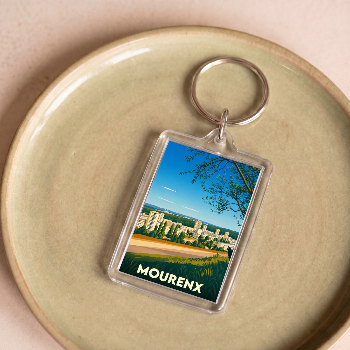 Porte-clés souvenir de la ville de Mourenx avec une illustration stylisée de son paysage urbain.