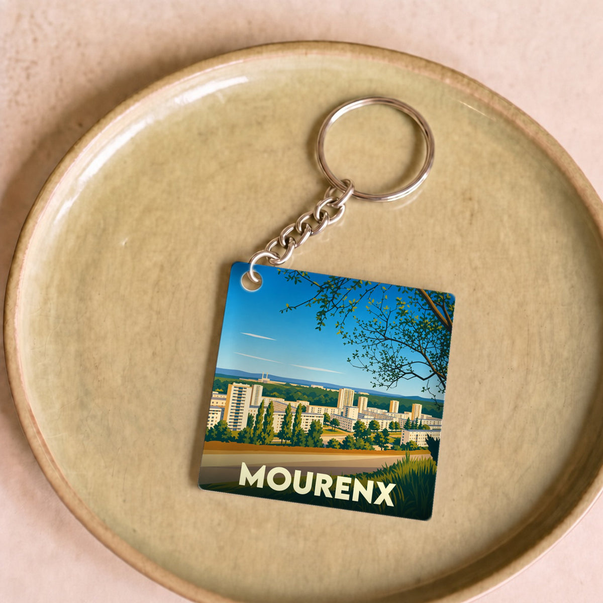 Porte-clés souvenir de la ville de Mourenx avec une illustration stylisée de son paysage urbain.