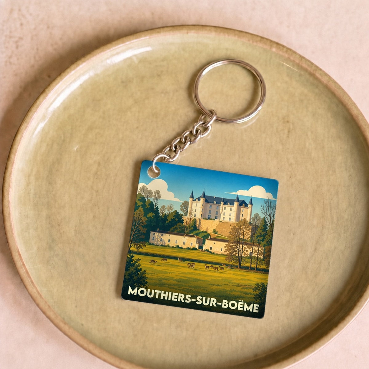 Porte-clés souvenir de Mouthiers-sur-Boëme avec une illustration stylisée de son château et de sa campagne.