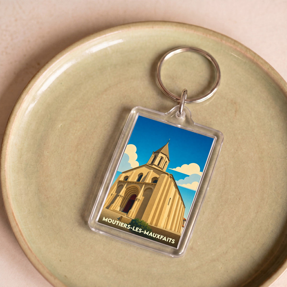 Porte-clés souvenir de la ville de Moutiers-les-Mauxfaits avec une illustration stylisée de son église.
