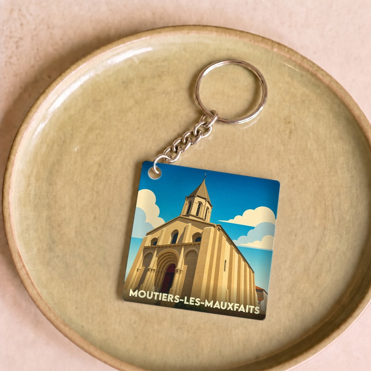 Porte-clés souvenir de la ville de Moutiers-les-Mauxfaits avec une illustration stylisée de son église.