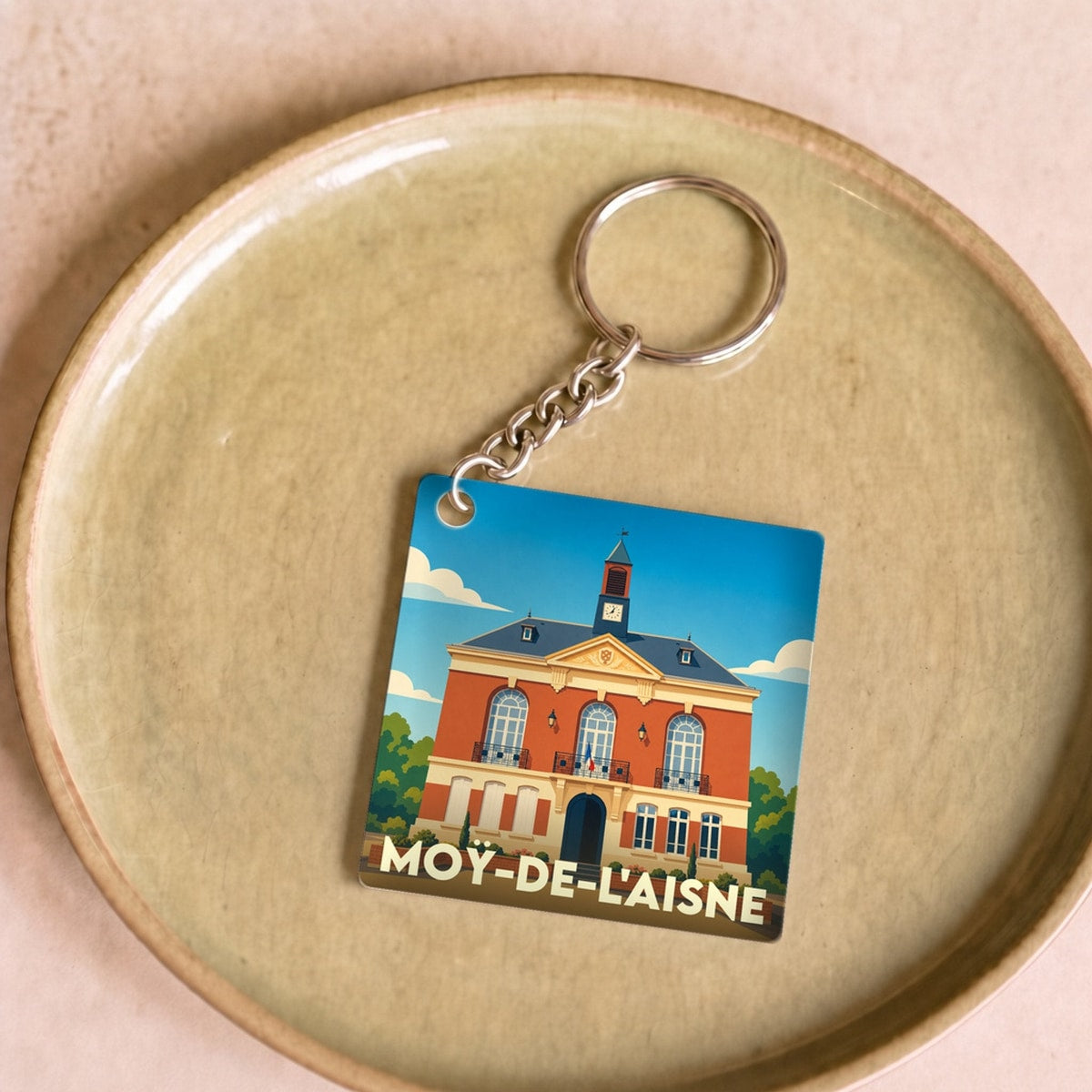 Porte-clés souvenir de la ville de Moÿ-de-l'Aisne avec une illustration stylisée de sa mairie.