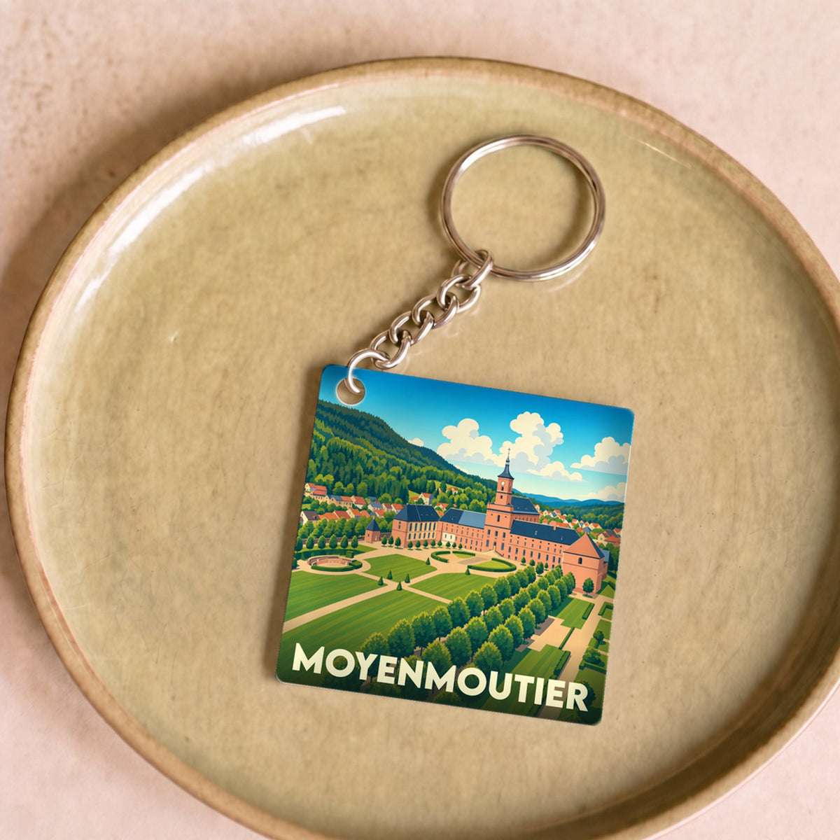 Porte-clés souvenir de la ville de Moyenmoutier avec une illustration stylisée.