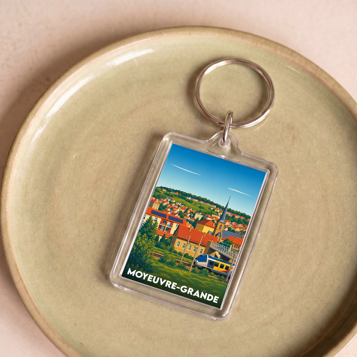 Porte-clés souvenir de la ville de Moyeuvre-Grande avec une illustration stylisée.