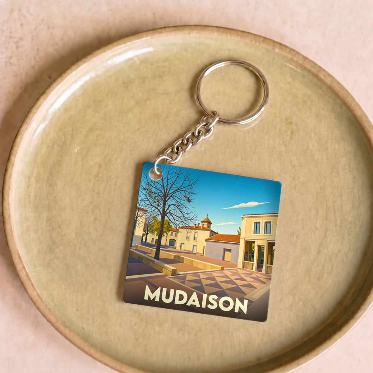 Porte-clés souvenir de la ville de Mudaison avec une illustration stylisée.
