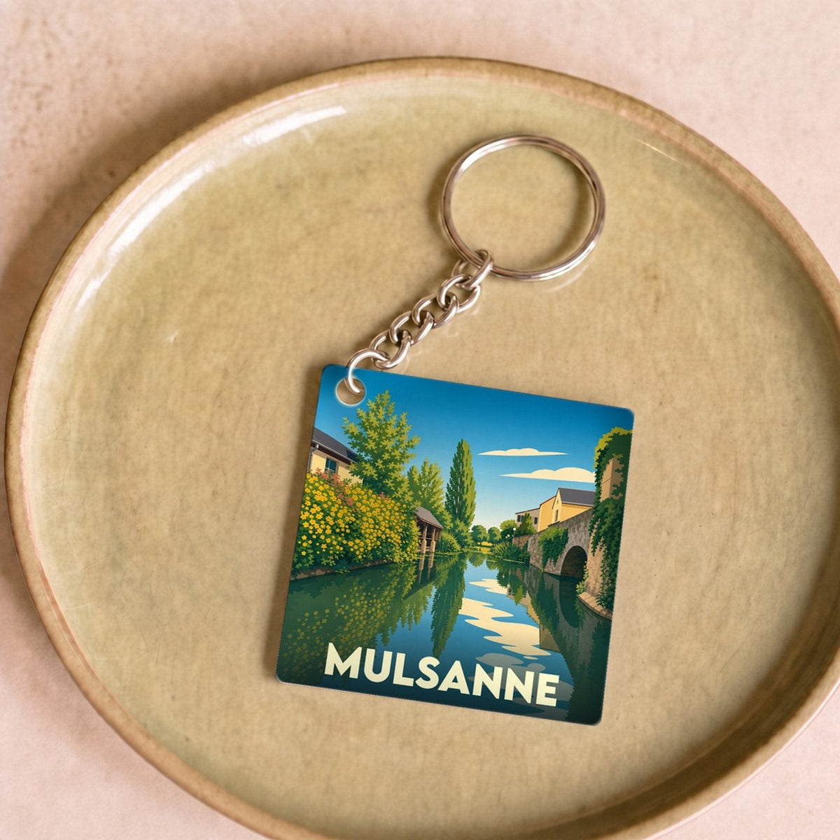 Porte-clés souvenir de la ville de Mulsanne avec une illustration stylisée d'un paysage au bord de l'eau.