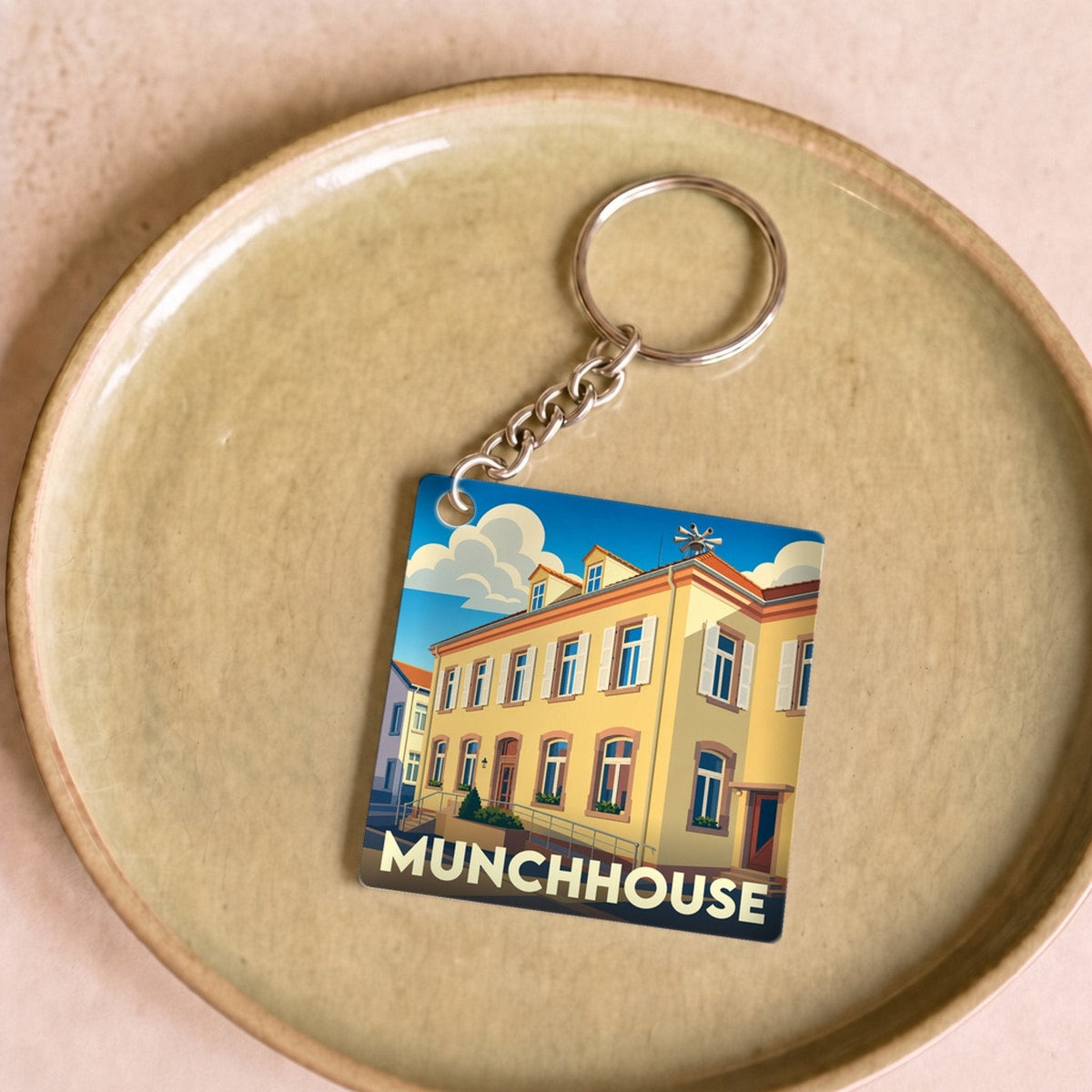 Porte-clés souvenir de la ville de Munchhouse avec une illustration stylisée d'un bâtiment coloré.