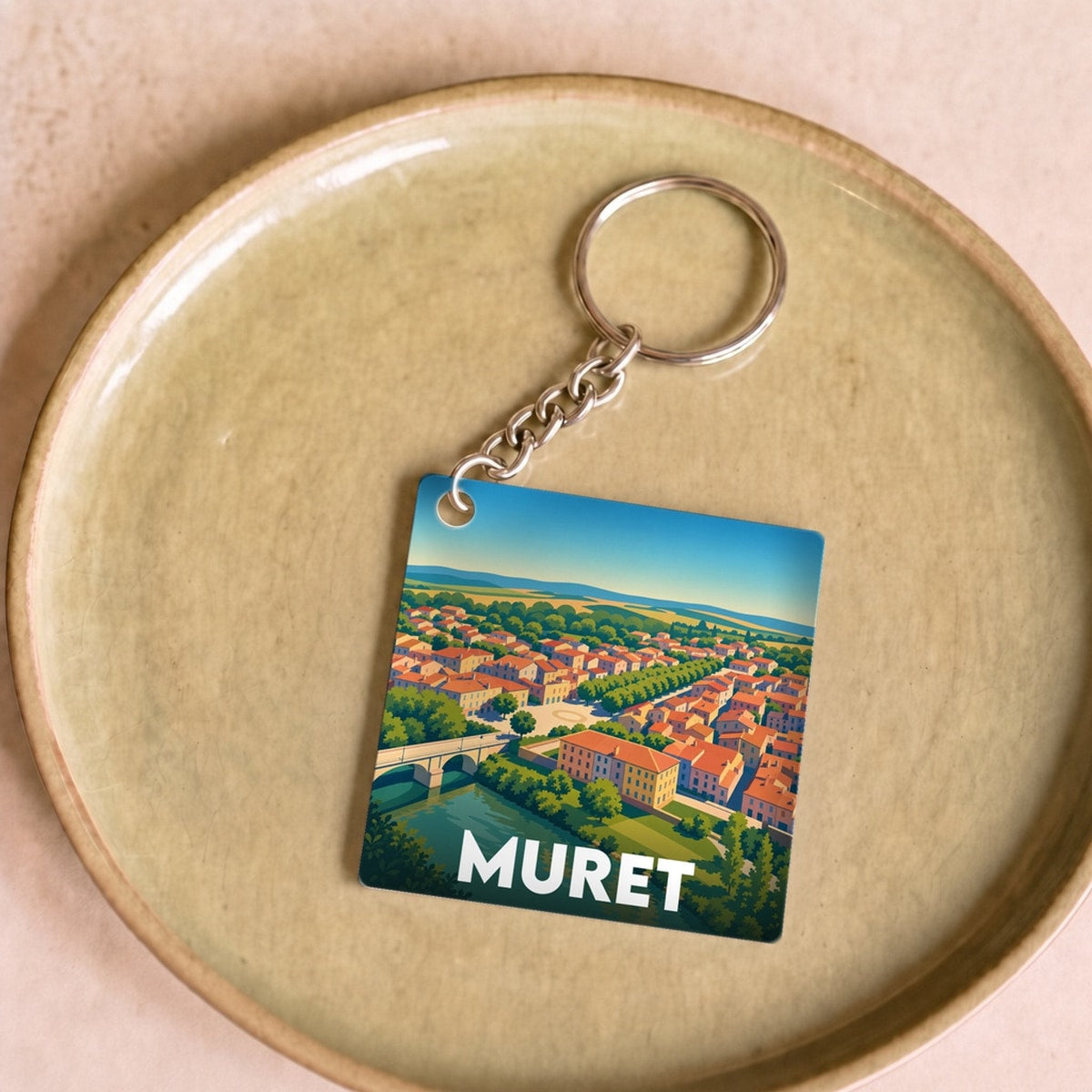 Porte-clés souvenir de la ville de Muret avec une illustration stylisée d'un paysage urbain.
