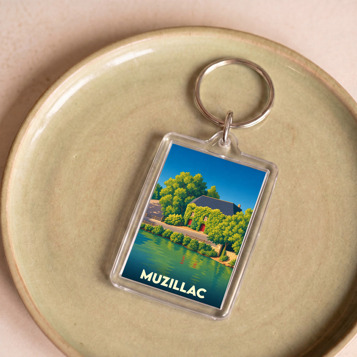 Porte-clés souvenir de la ville de Muzillac avec une illustration stylisée d'une maison au bord de l'eau.
