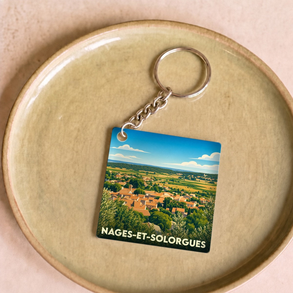 Porte-clés souvenir de la ville de Nages-et-Solorgues avec une illustration de paysage panoramique.