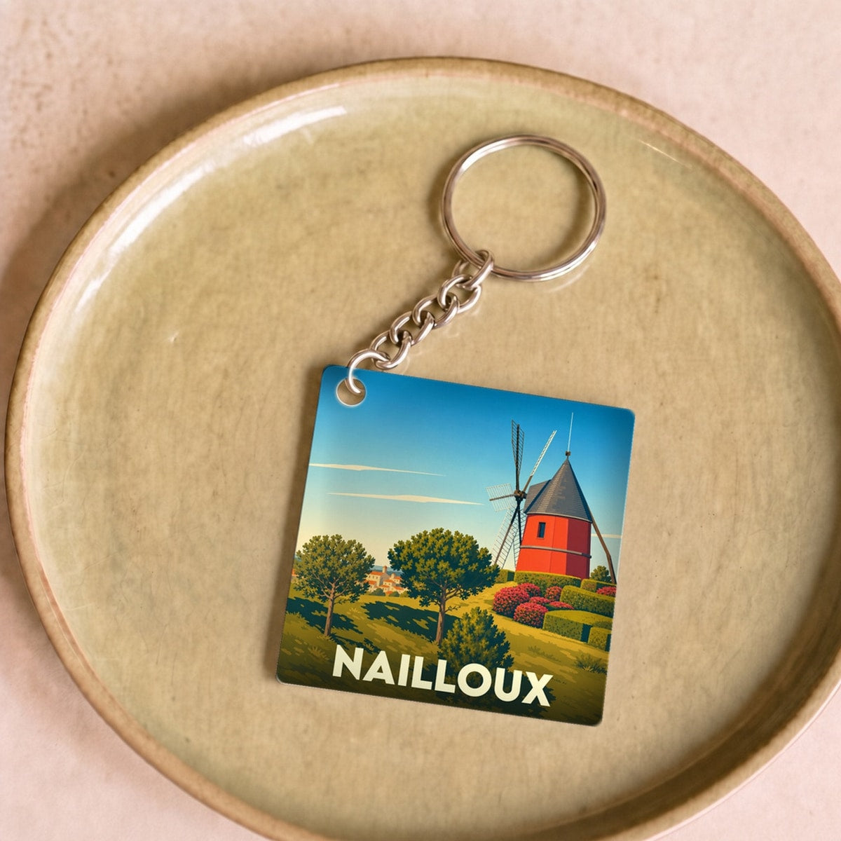 Porte-clés souvenir de la ville de Nailloux avec une illustration stylisée d'un moulin à vent rouge.