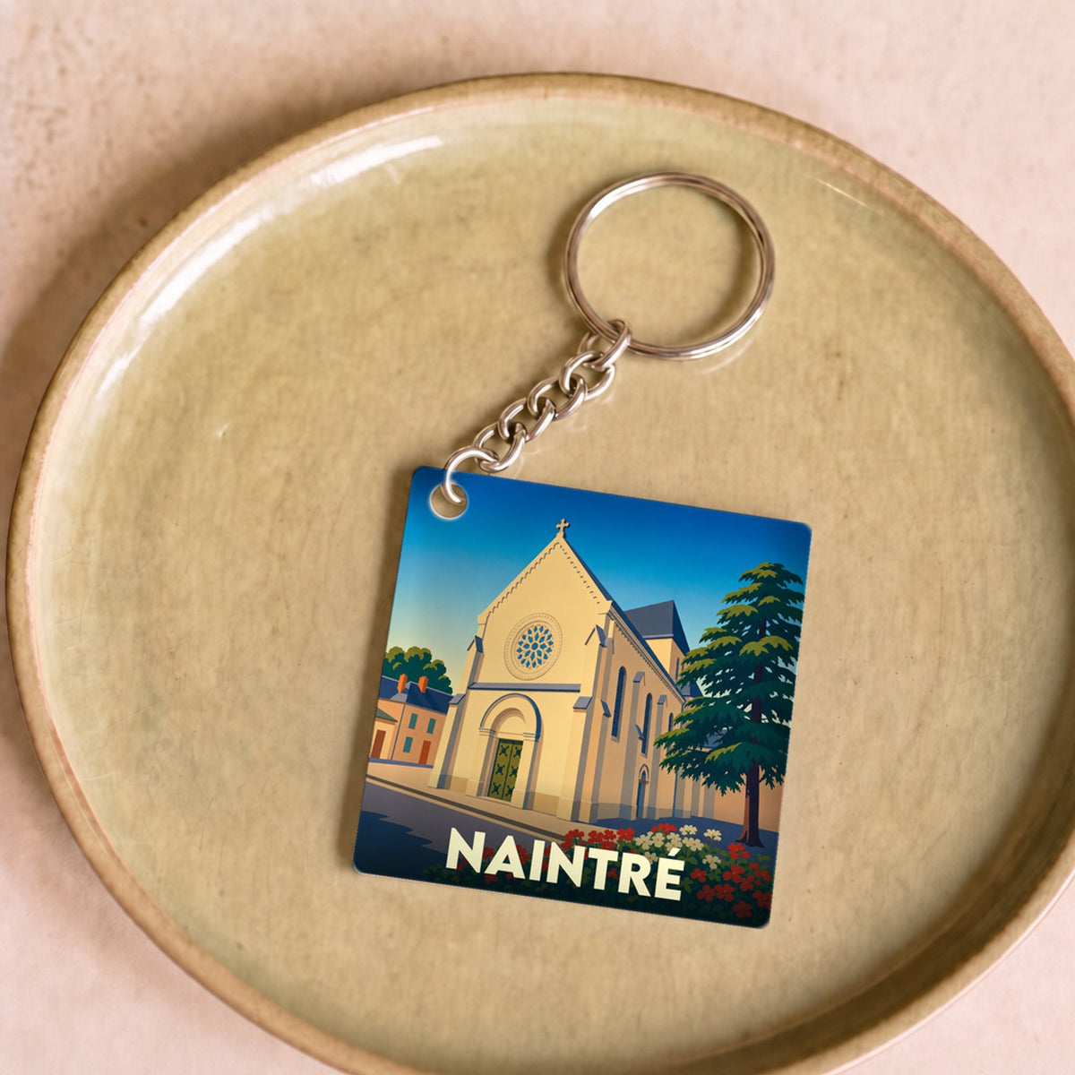 Porte-clés souvenir de la ville de Naintré avec une illustration stylisée de son église.