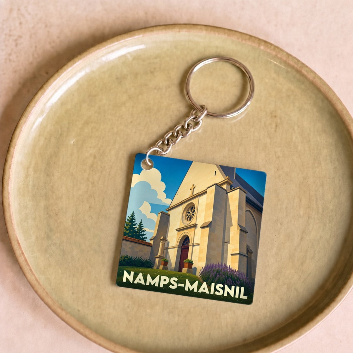 Porte-clés souvenir de la ville de Namps-Maisnil avec une illustration stylisée de son église.