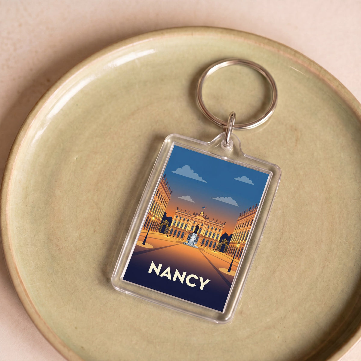 Porte-clés souvenir de la ville de Nancy avec une illustration stylisée de la place Stanislas.