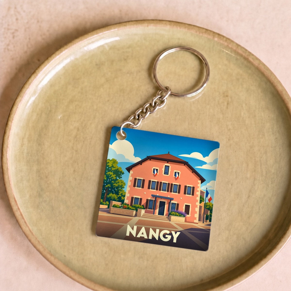 Porte-clés souvenir de la ville de Nangy avec une illustration stylisée d'un bâtiment traditionnel.