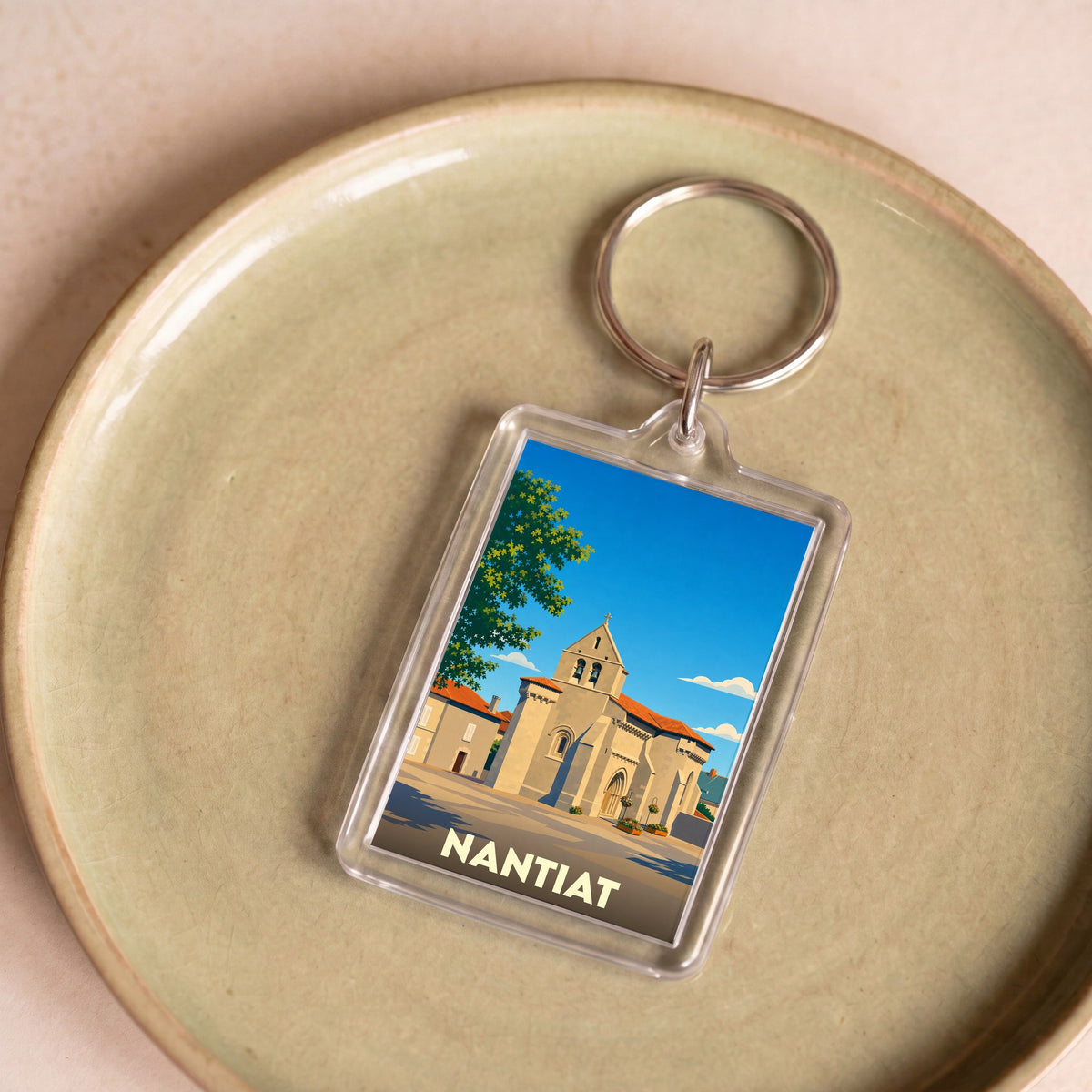 Porte-clés souvenir de la ville de Nantiat avec une illustration stylisée de son église.