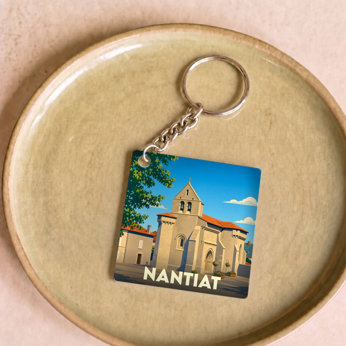 Porte-clés souvenir de la ville de Nantiat avec une illustration stylisée de son église.