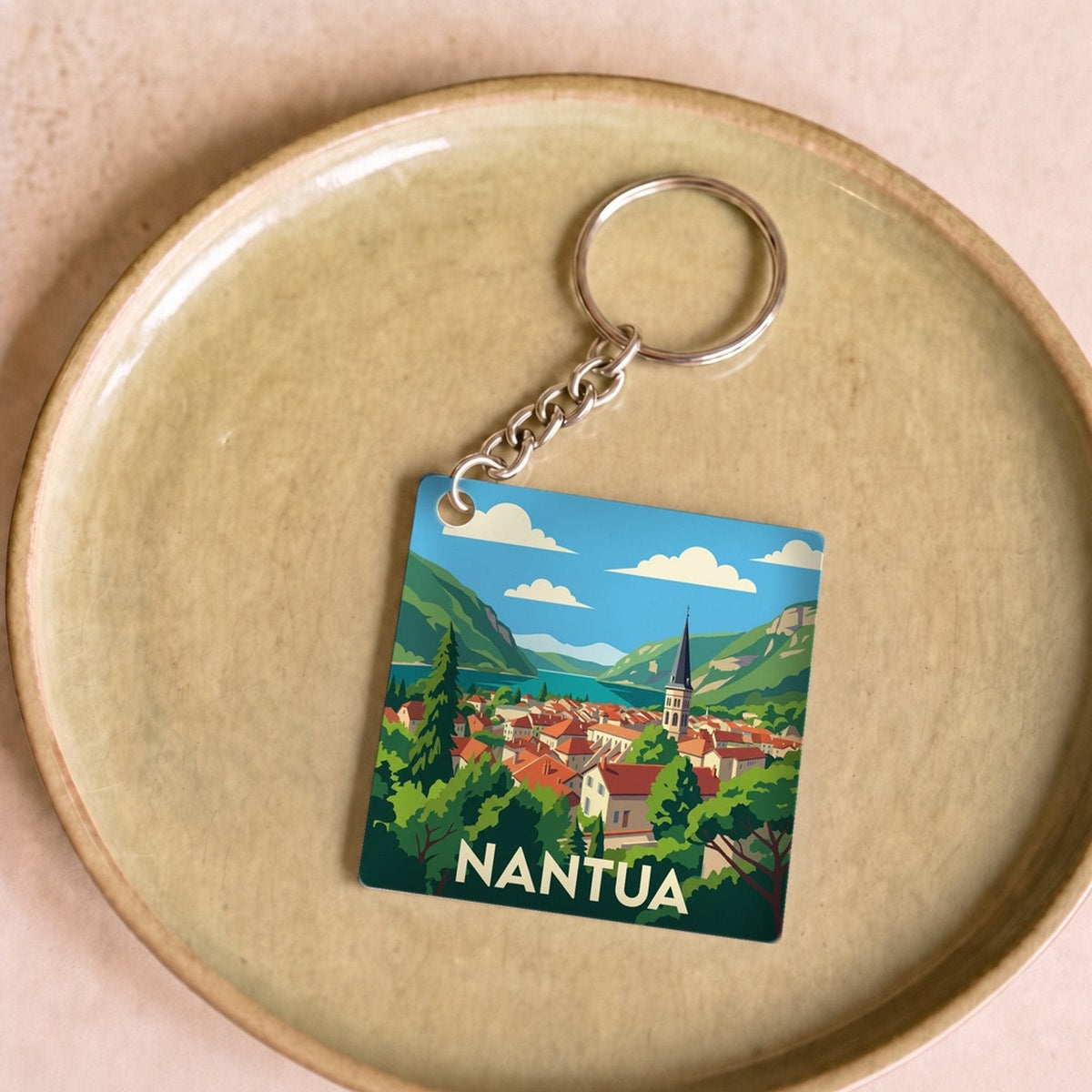 Porte-clés souvenir de la ville de Nantua avec une illustration stylisée.