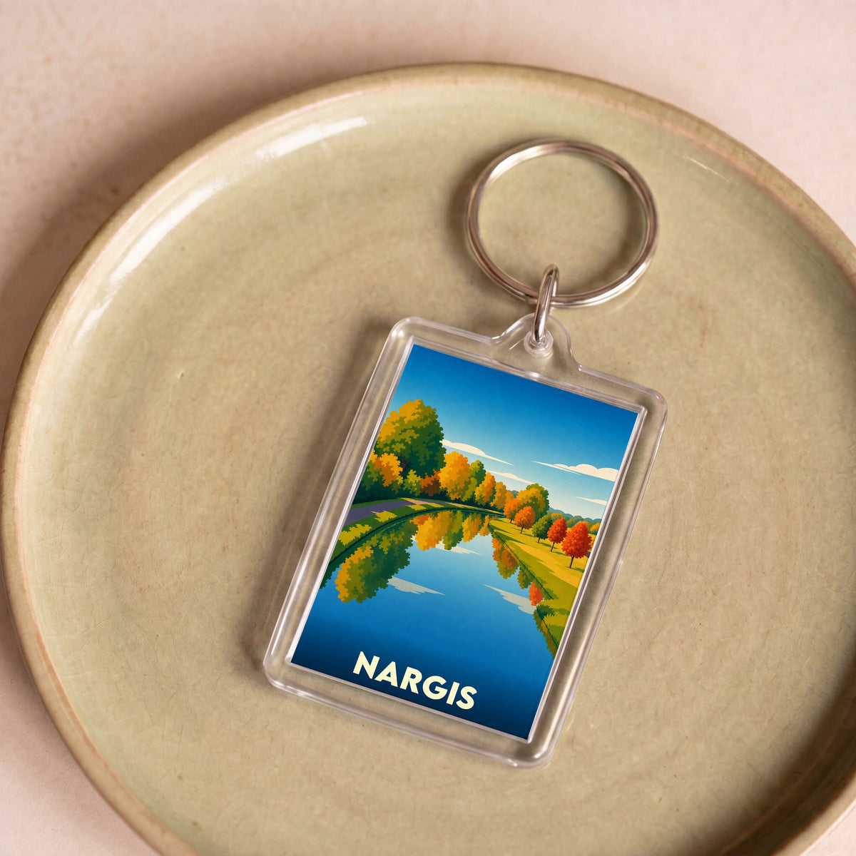 Porte-clés souvenir de la ville de Nargis avec une illustration stylisée d'un paysage d'automne se reflétant dans l'eau.