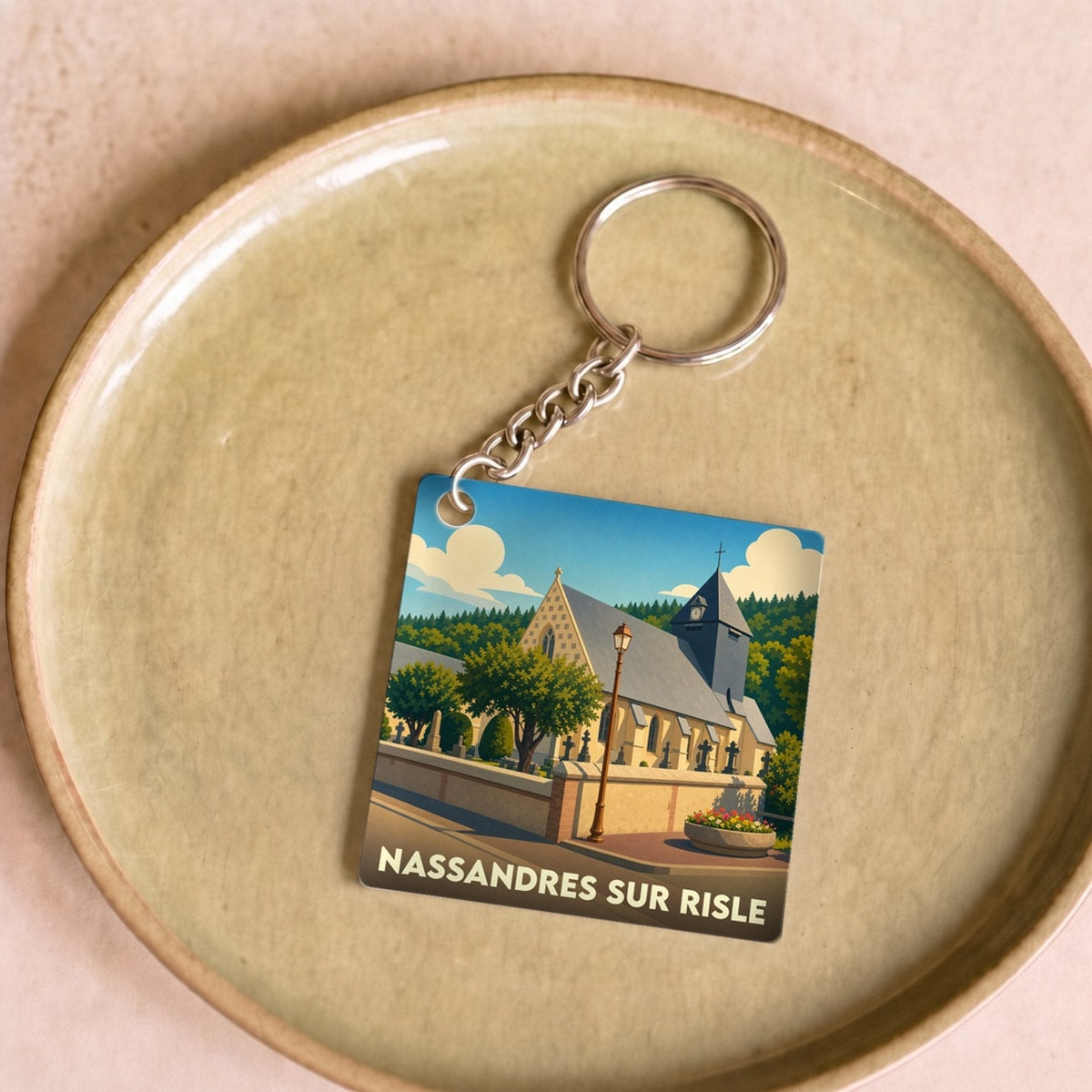Porte-clés souvenir de la ville de Nassandres sur Risle avec une illustration stylisée de son église.