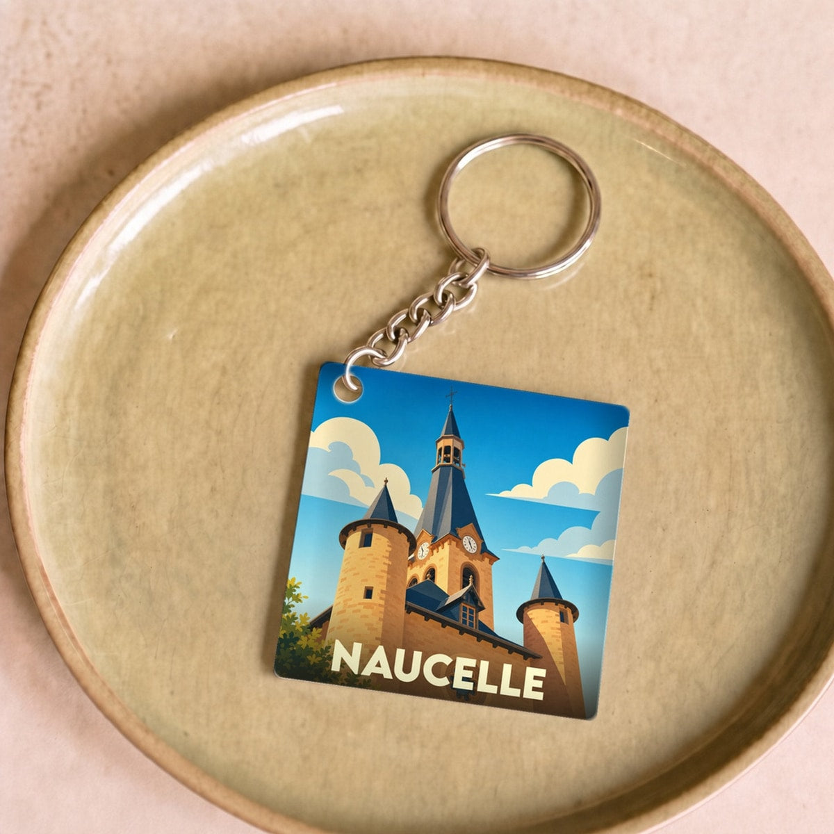 Porte-clés souvenir de la ville de Naucelle avec une illustration stylisée de son église.