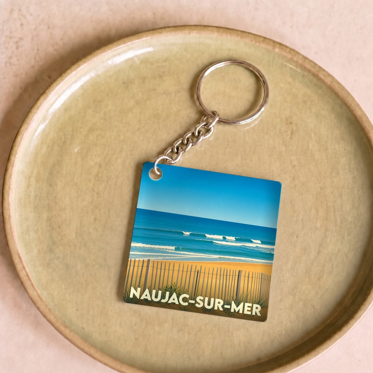 Porte-clés souvenir de Naujac-sur-Mer avec une illustration stylisée de sa plage.