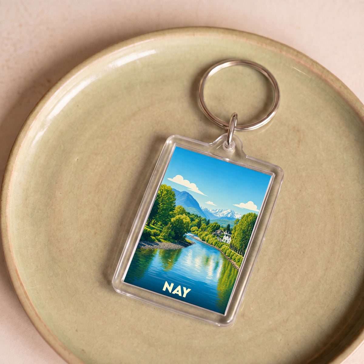 Porte-clés souvenir de la ville de Nay avec une illustration stylisée des Pyrénées et du Gave.