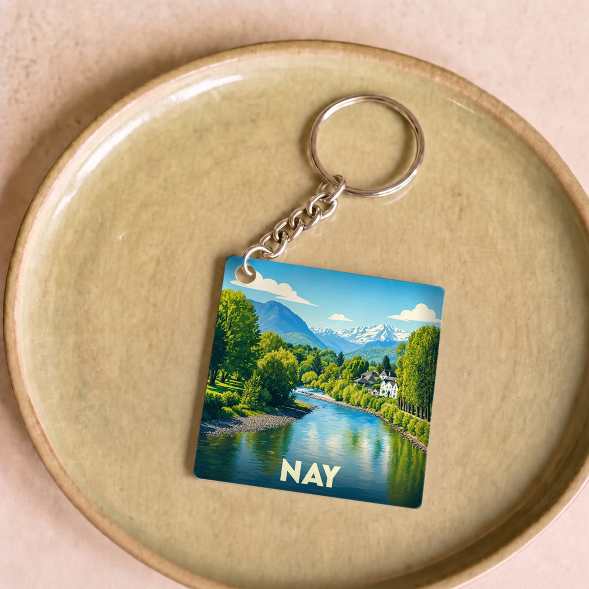 Porte-clés souvenir de la ville de Nay avec une illustration stylisée des Pyrénées et du Gave.