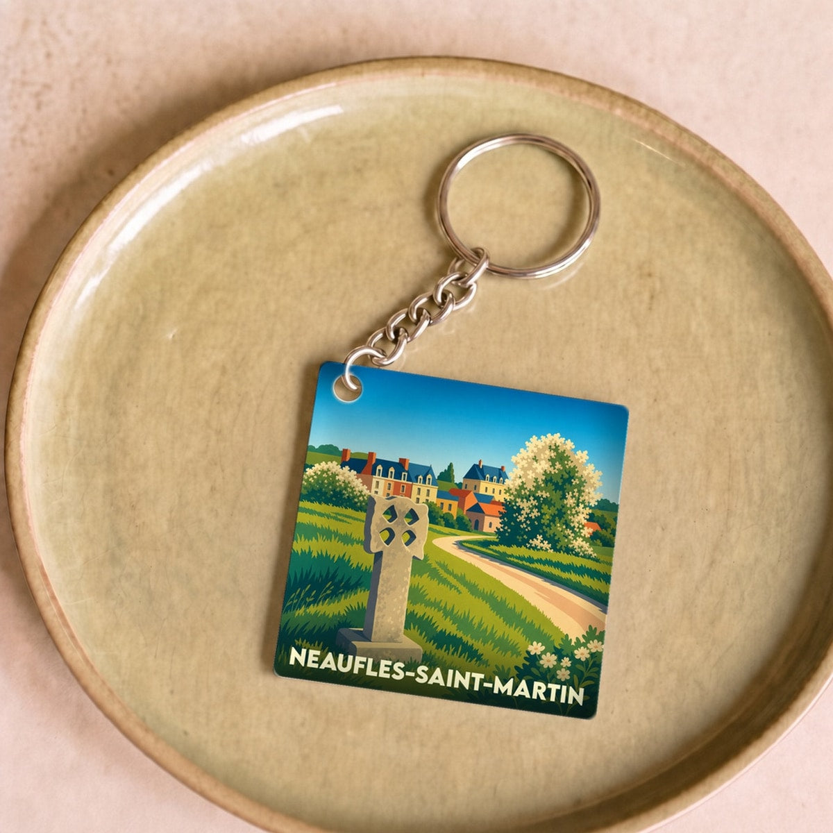 Porte-clés souvenir de la ville de Neaufles-Saint-Martin avec une illustration stylisée d'un paysage champêtre.