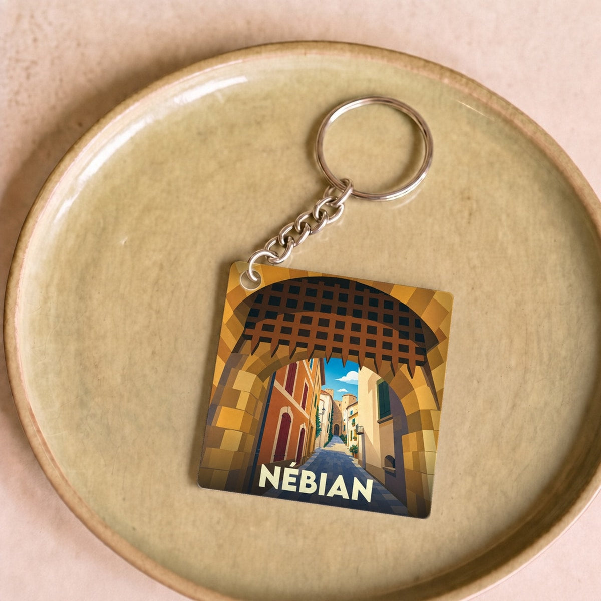 Porte-clés souvenir de la ville de Nébian avec une illustration stylisée d'une ruelle médiévale.