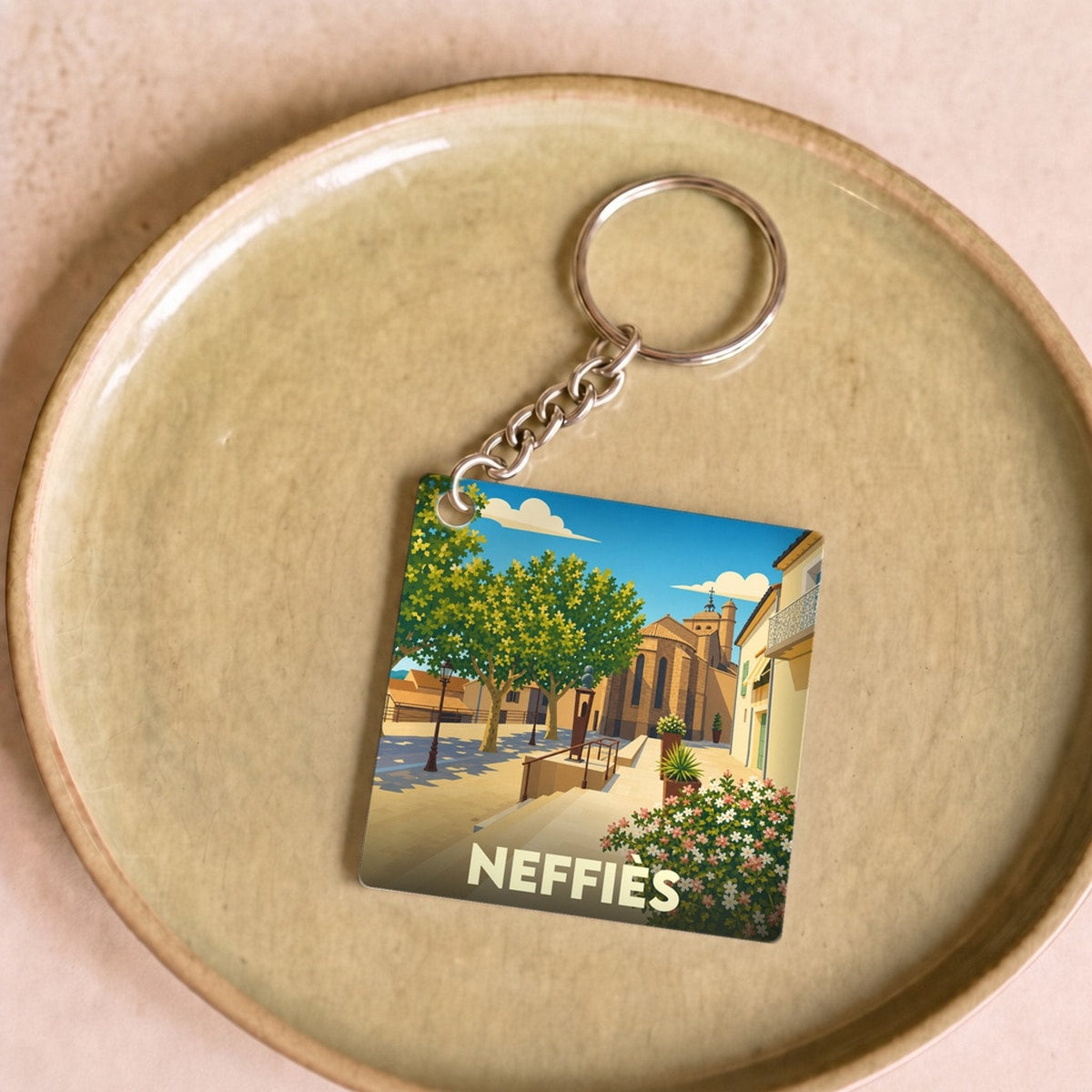 Porte-clés souvenir de la ville de Neffiès avec une illustration stylisée.