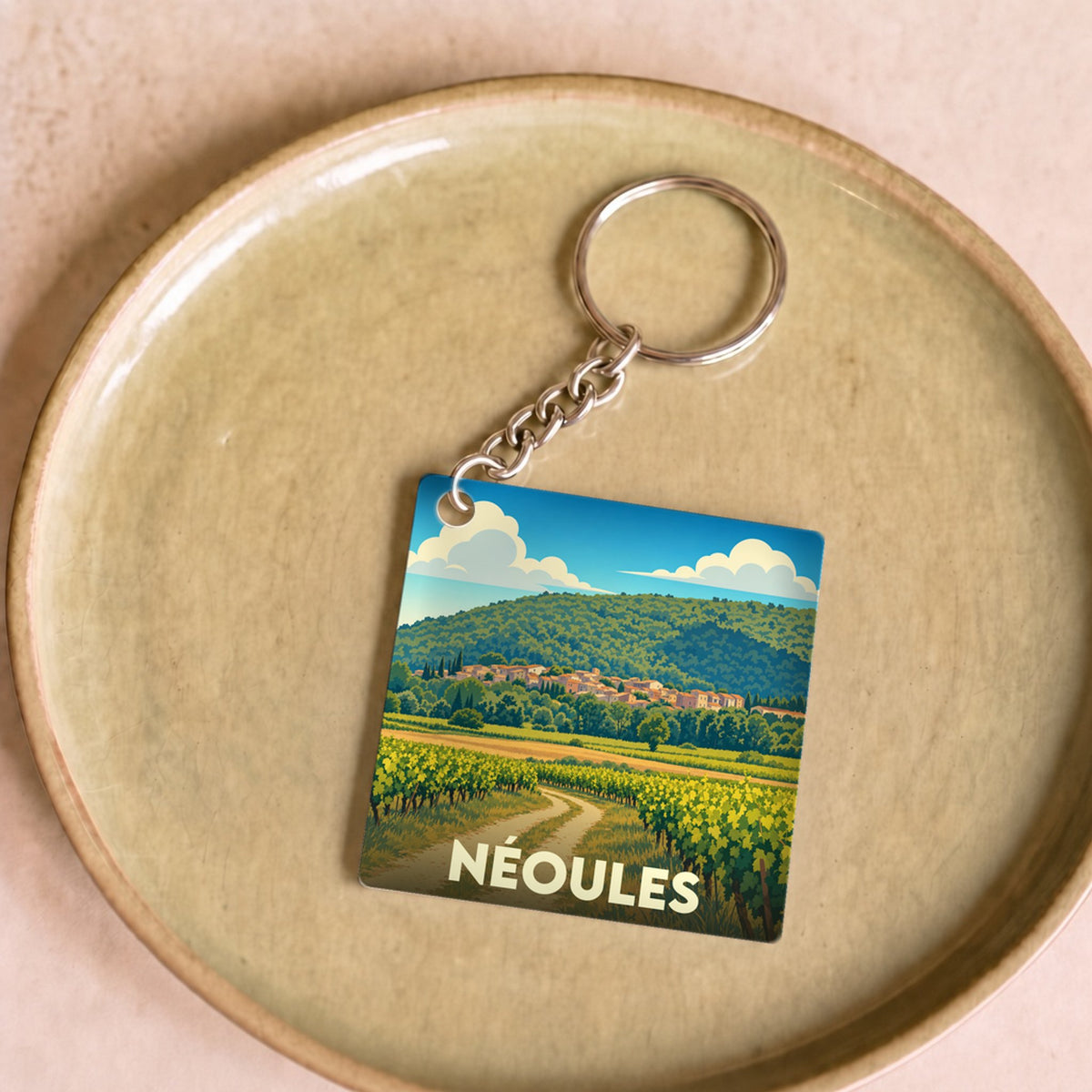 Porte-clés souvenir de la ville de Néoules avec une illustration stylisée de son paysage de vignobles.