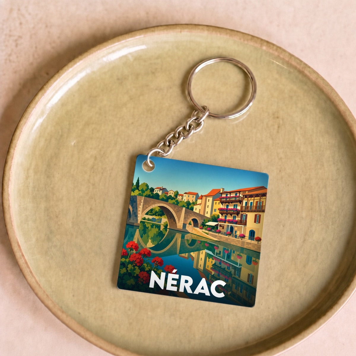 Porte-clés souvenir de la ville de Nérac avec une illustration colorée et stylisée de son pont emblématique.