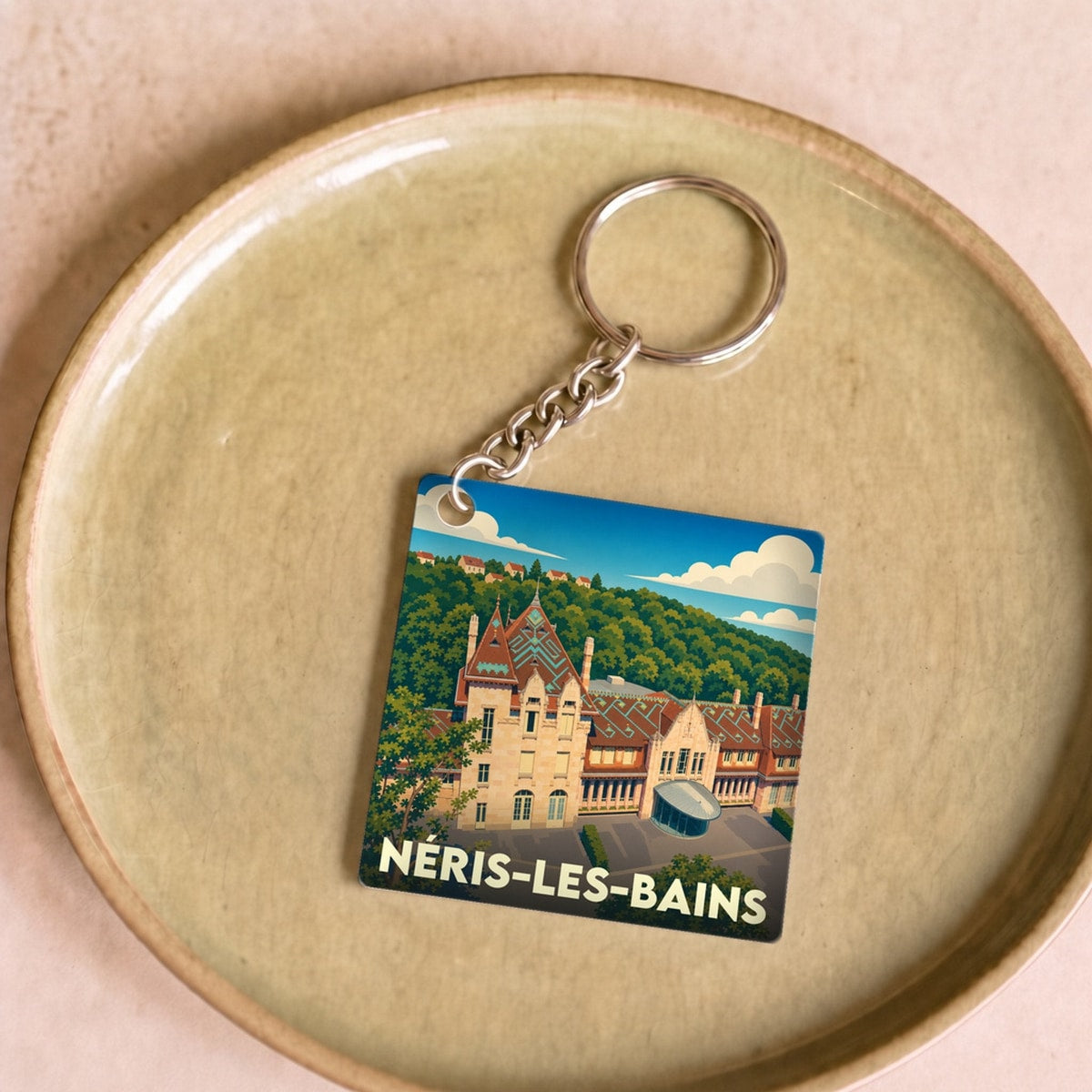 Porte-clés souvenir de la ville de Néris-les-Bains avec une illustration stylisée de ses thermes.