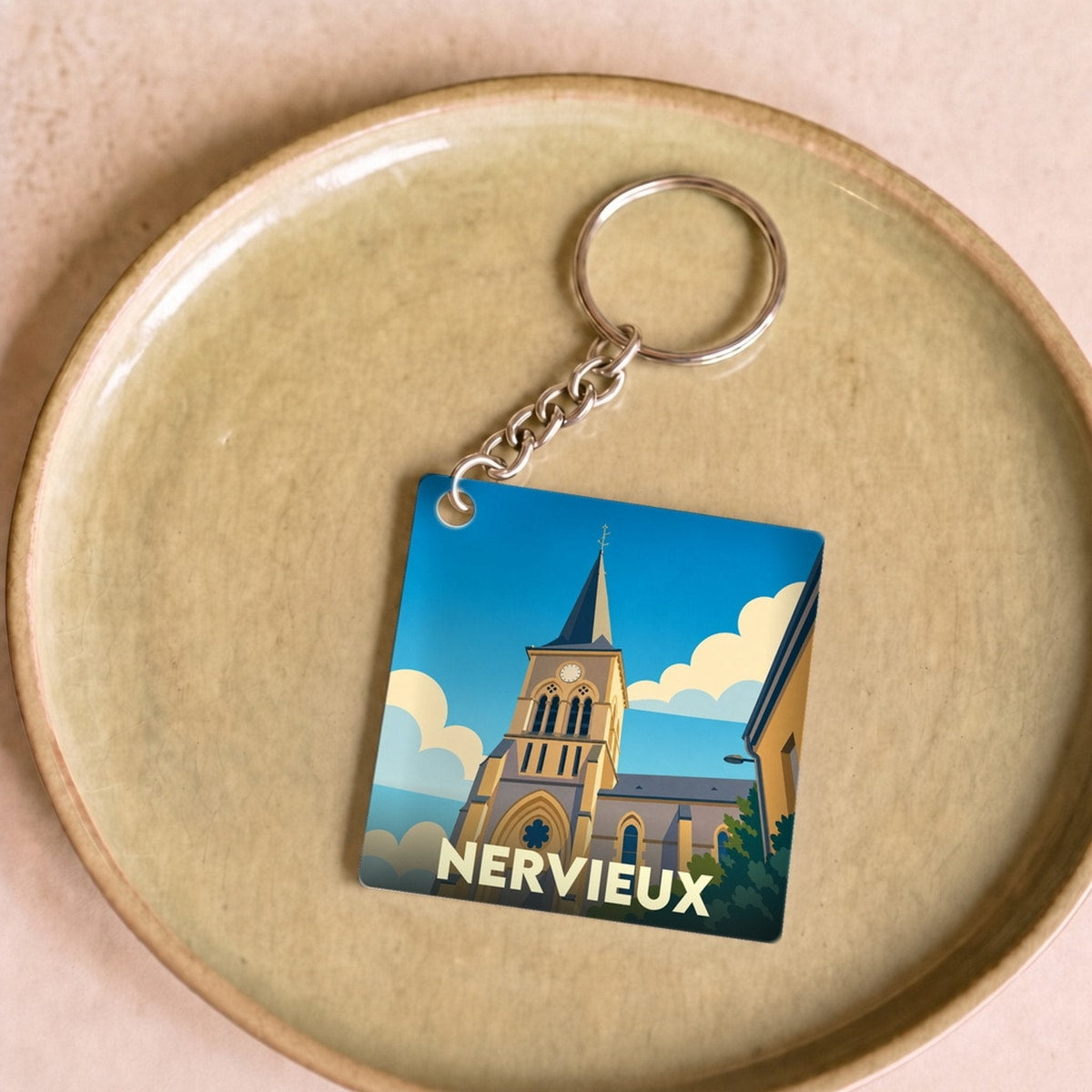 Porte-clés souvenir de la ville de Nervieux avec une illustration stylisée de son église.