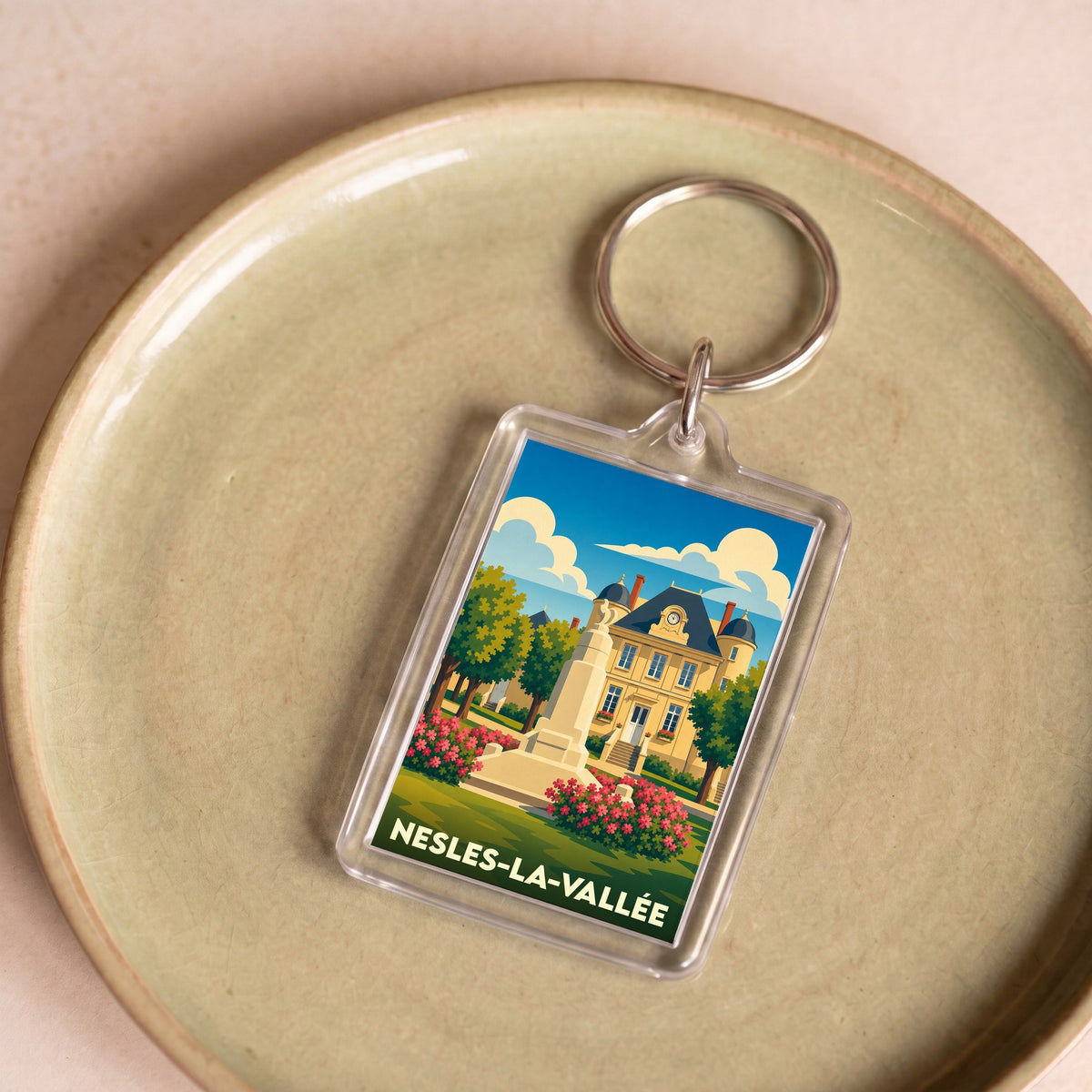 Porte-clés souvenir de la ville de Nesles-la-Vallée avec une illustration stylisée.