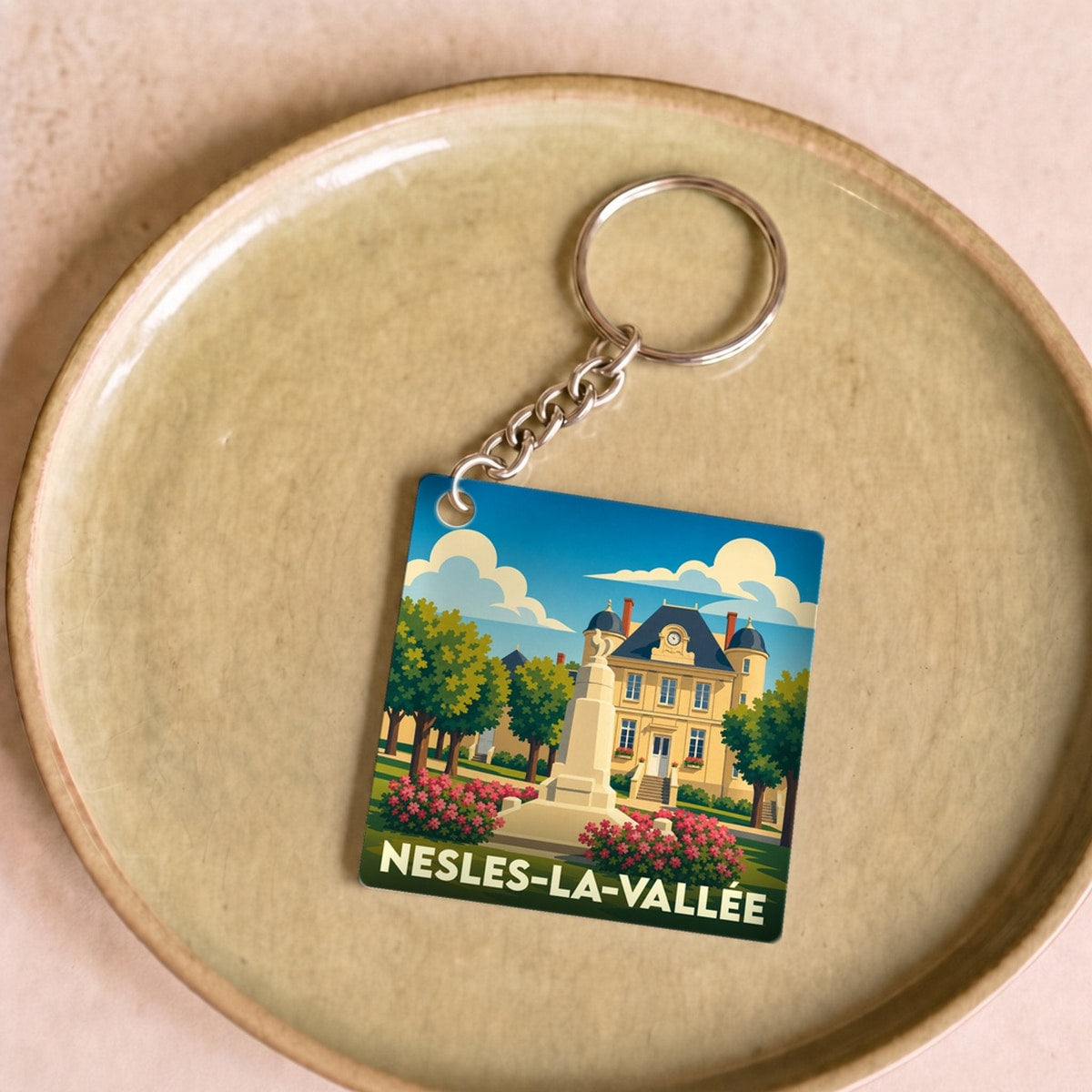 Porte-clés souvenir de la ville de Nesles-la-Vallée avec une illustration stylisée.