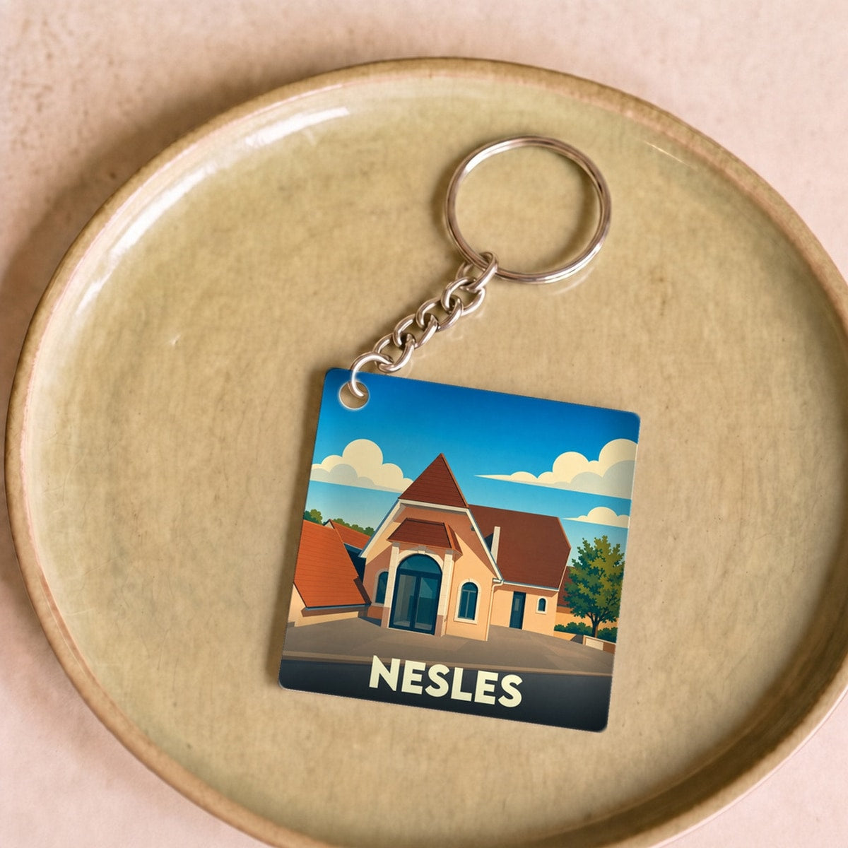 Porte-clés souvenir de la ville de Nesles avec une illustration stylisée.