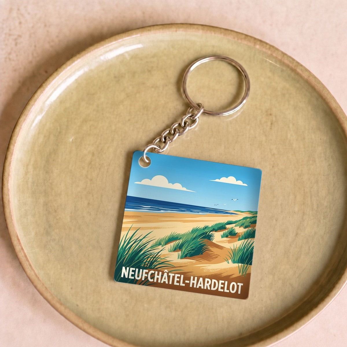 Porte-clés souvenir de la ville de Neufchâtel-Hardelot avec une illustration stylisée de dunes et de mer.