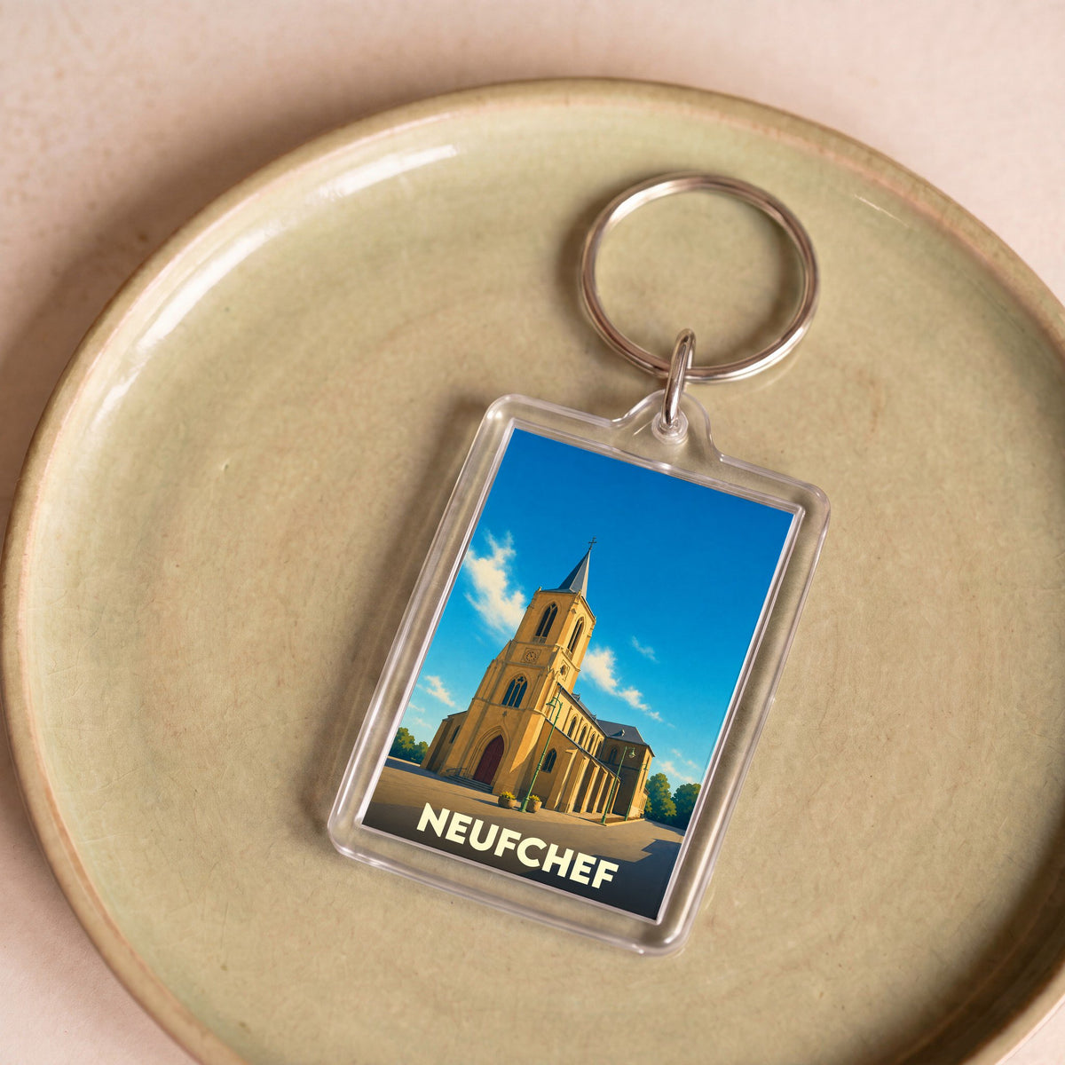 Porte-clés souvenir de la ville de Neufchef avec une illustration stylisée de son église.