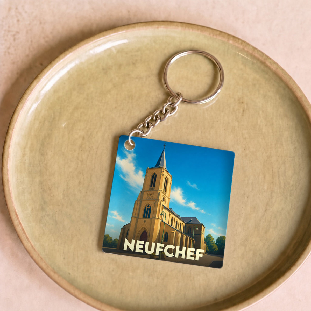 Porte-clés souvenir de la ville de Neufchef avec une illustration stylisée de son église.
